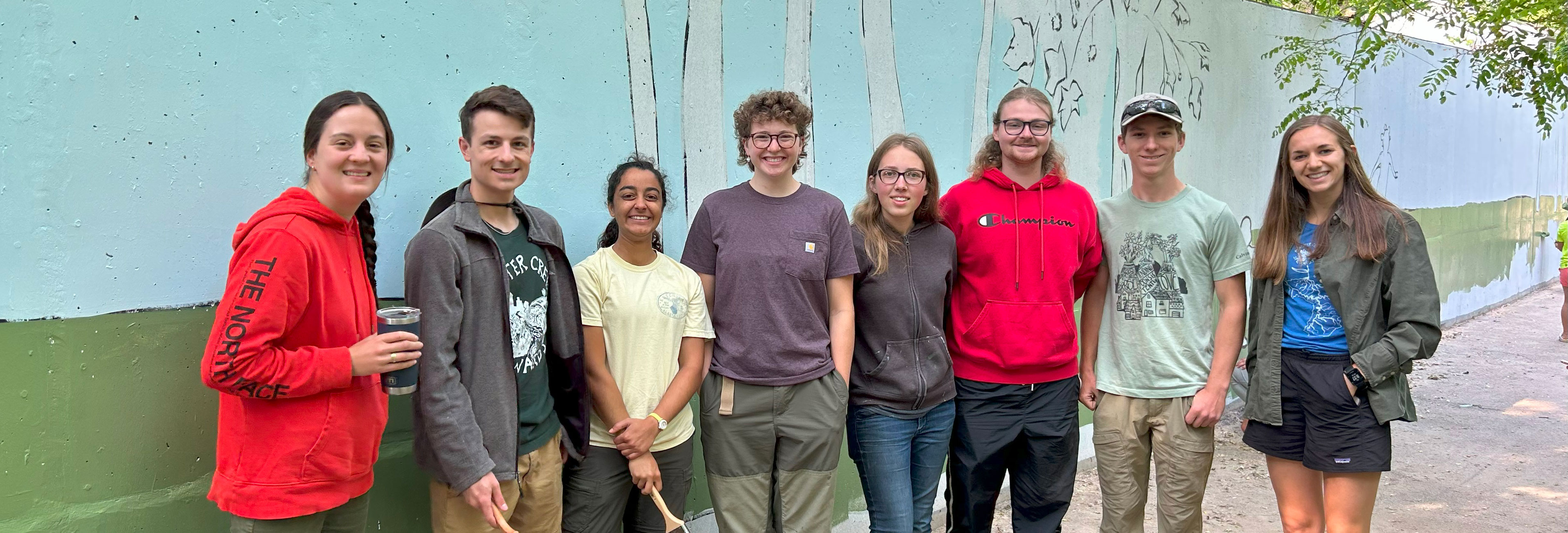 Young volunteers posing in front of a mural