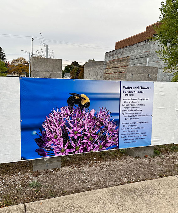 Printed banner on a fence with bee photograph and poetry