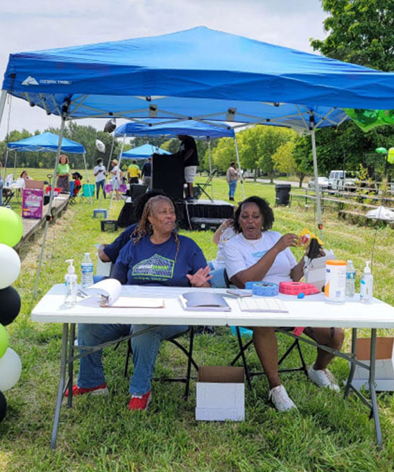 Two women sitting at a table under a canopy talking