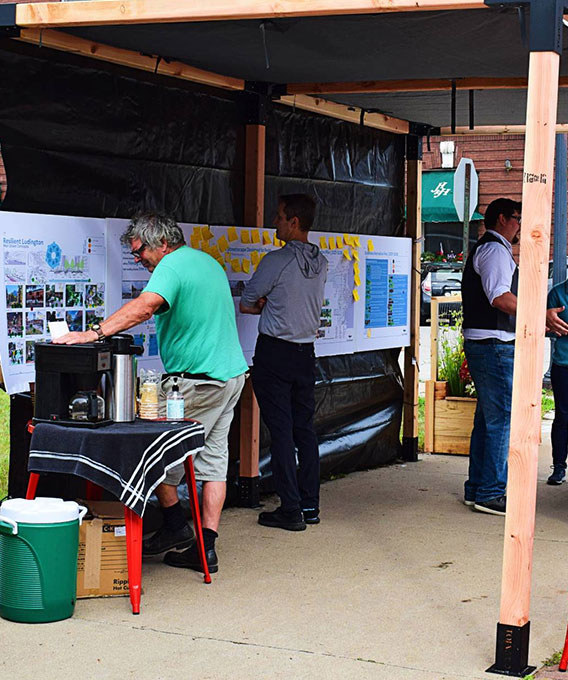 People gathering around a planning board filled with drawings and post-it notes