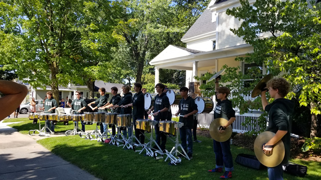 Photo of drum corps playing along a sidewalk