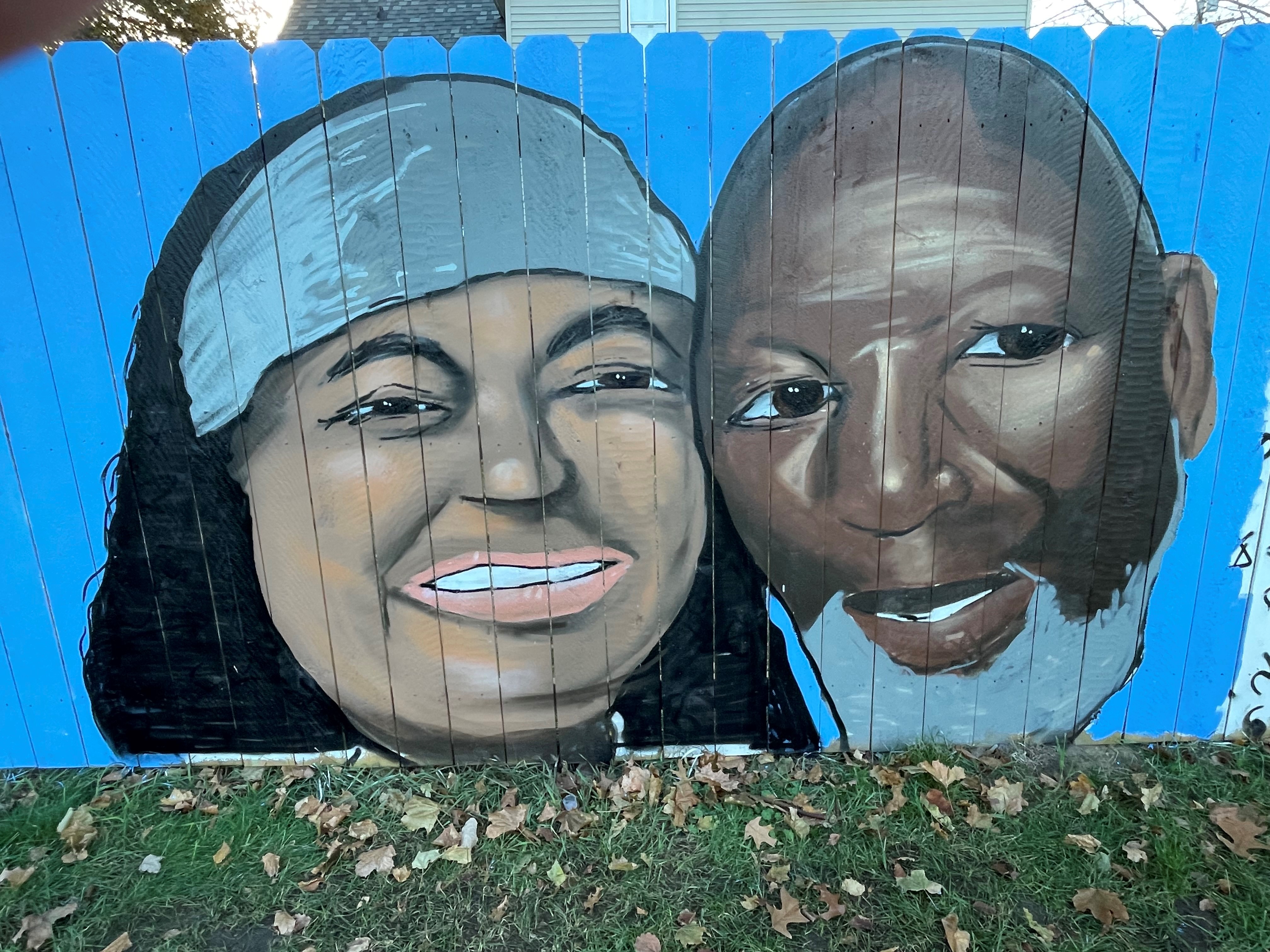 Mural of two people painted on a fence